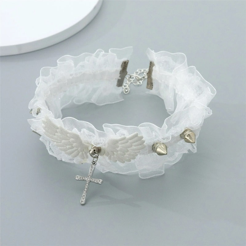 White fairy grunge lace choker necklace with angel wings and silver spikes on a grey background, displaying the hanging crystal cross and back chain closure.