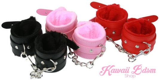 A collection of premium fluffy faux leather restraint cuffs in black, pastel pink, and vibrant red, connected by silver chains on a crisp white background.