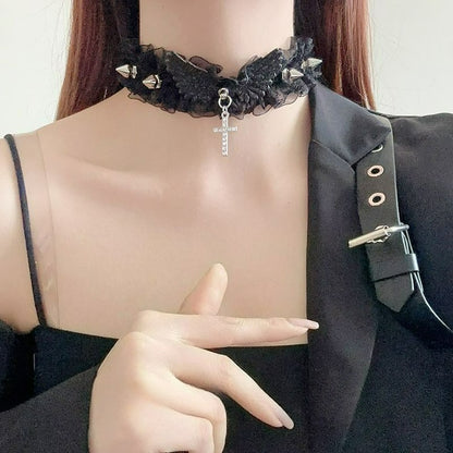 Detailed shot of a person wearing the black spiked lace choker with a central angel wing centerpiece and a cross. A full view of the worn alternative necklace.