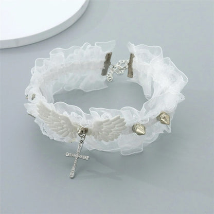 White fairy grunge lace choker necklace with angel wings and silver spikes on a grey background, displaying the hanging crystal cross and back chain closure.