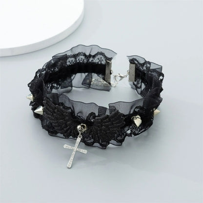 Black dark coquette lace choker necklace with dark angel wings and silver spikes on a grey background, displaying the hanging crystal cross and back chain closure.