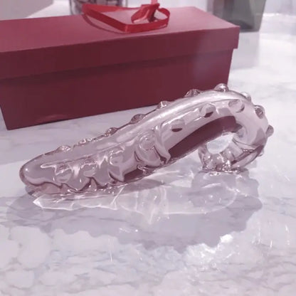 Elegant crystal clear glass tentacle wand resting on a marble surface next to a luxurious red gift box.
