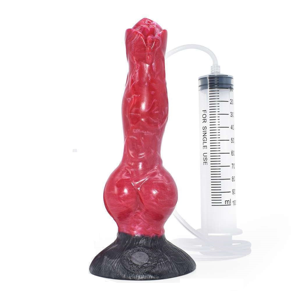 Dark cherry red and black marbled fantasy squirt dildo standing upright next to its included liquid syringe.