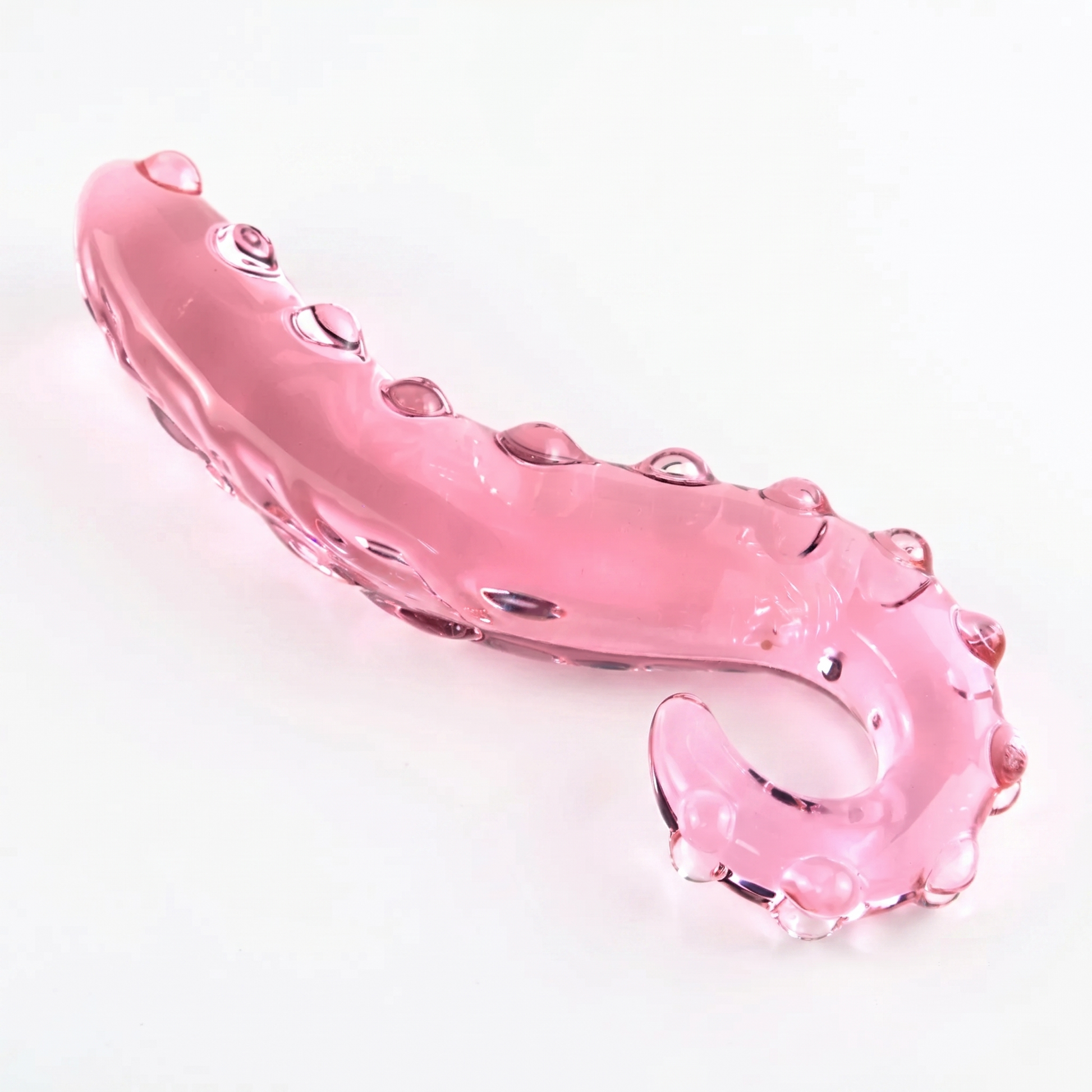 Large pastel pink borosilicate glass tentacle dildo in the thick curl style with deep suction cup textures on a white background.