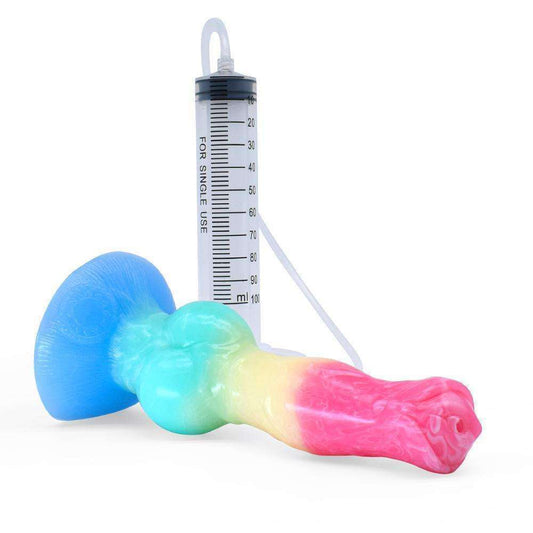 Pastel rainbow gradient squirt dildo lying down showing the clear syringe tube attached to its suction cup.