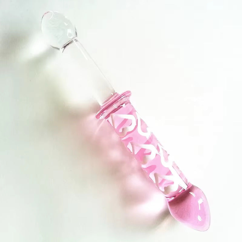 The kawaii pink and clear double ended glass dildo resting diagonally on a smooth surface.