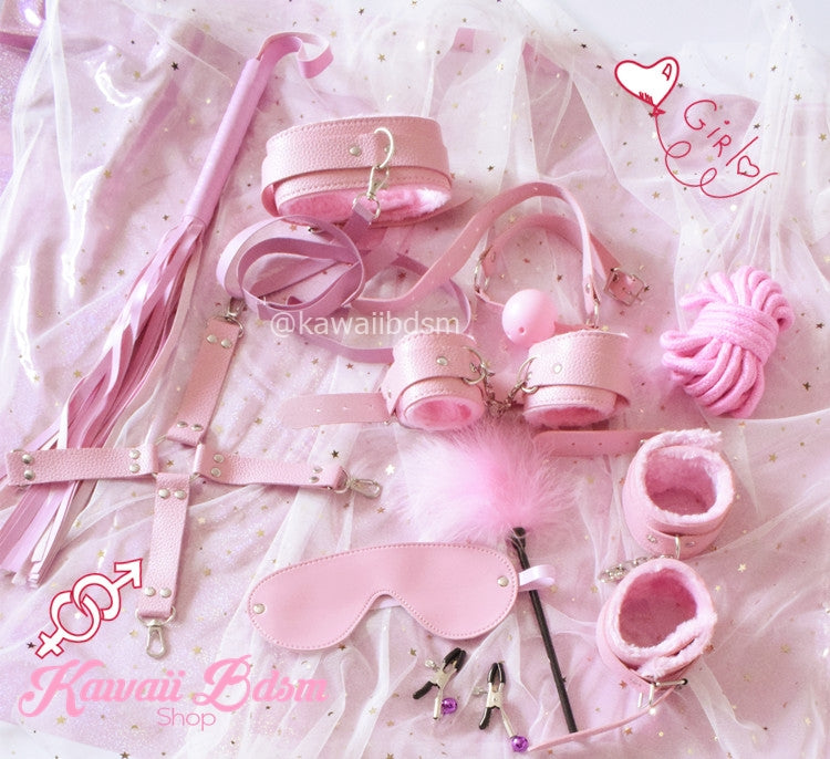 Aesthetic display of the 10-piece pastel pink bondage set scattered playfully on pink silk sheets.