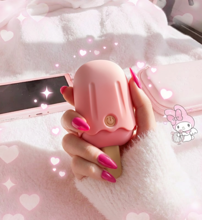 A hand with long pink stiletto nails holds the cute pink popsicle suction toy in front of a soft pink bed with sparkling edit effects, highlighting its trendy disguise design.