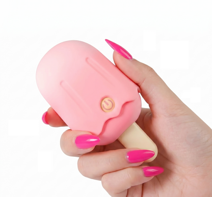 A close-up shot of a hand with long pink nails holding the compact pink popsicle sucker and vibrator to demonstrate its mini, travel-friendly size.