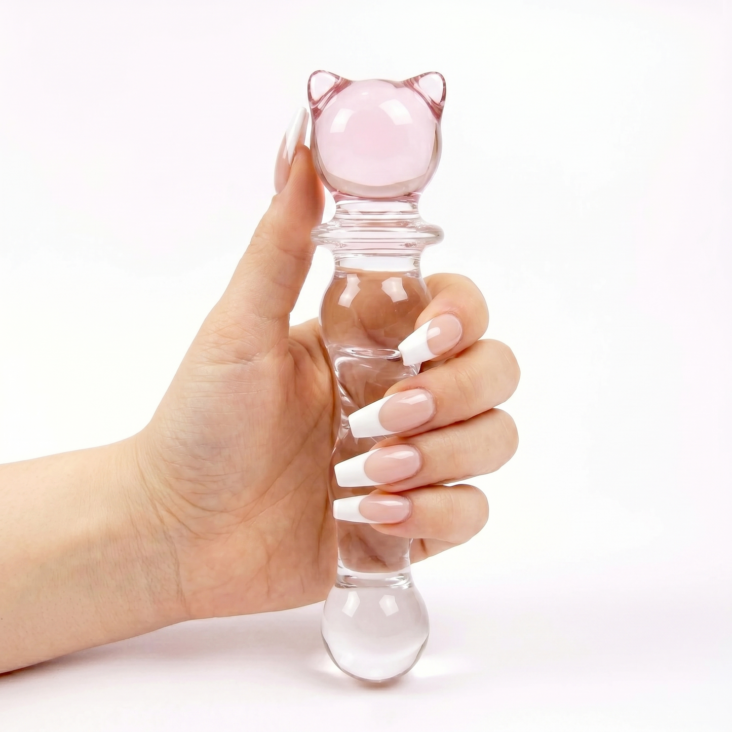 Hand holding the clear glass cat wand completely vertical against a clean white background, highlighting the pink kitten shape.