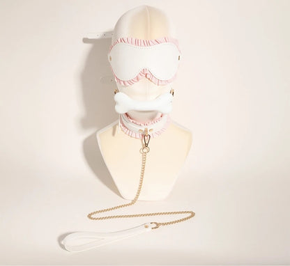 An elegant display of the white ruffled blindfold and matching collar with a rose gold leash attached, styled on a white boutique mannequin bust.