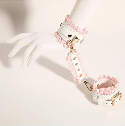 A boutique styling shot showing the white leather and pink ruffled wrist cuffs locked around a white mannequin hand, showcasing the premium rose gold hardware connectors.