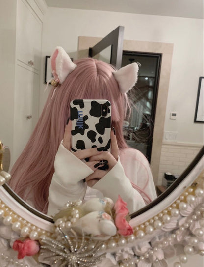 A girl with pink hair taking a mirror selfie while wearing kawaii kitten play ear clips.
