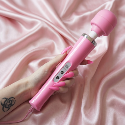 A hand holding the powerful pink magic wand vibrator against a luxurious pink satin background, highlighting the elegant and aesthetic bedroom toy design.