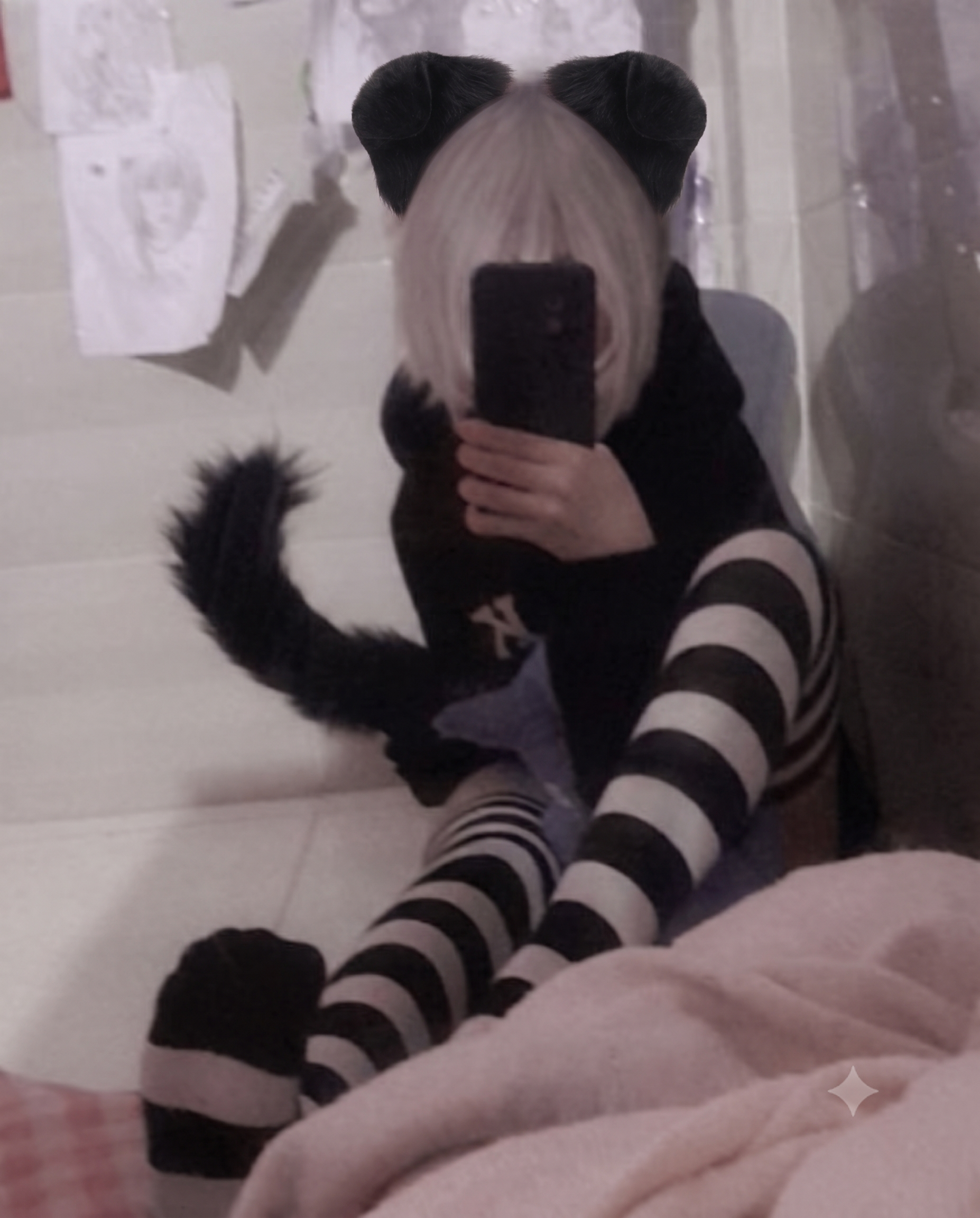 A lifestyle mirror selfie of a person with dark hair modeling a kawaii pet play aesthetic, wearing a black top, a thick black leather submissive collar with a metal tag, and cute fluffy white and brown animal ears.
