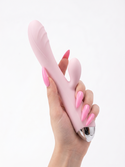 A hand holding the baby pink Pastel Dream Rabbit Vibrator upright, emphasizing the curved shaft for G-spot stimulation and ergonomic shape.