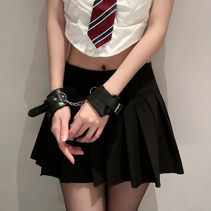 A stylish lifestyle shot of a model wearing a black pleated skirt and classic black fluffy lined wrist cuffs, showcasing the SFW cosplay aesthetic.