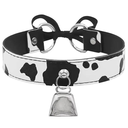 Front view of a cow print kitten play collar featuring a shiny silver bell.