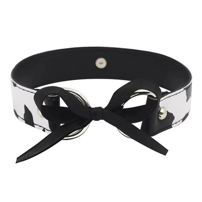 Detailed view of the adjustable ribbon tie and O-ring closure on a cow print collar.