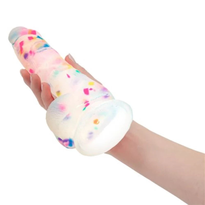 A hand holding the colorful kawaii confetti dildo horizontally, demonstrating the realistic veining details and comfortable grip.