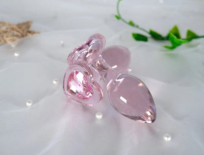 uxury hypoallergenic pink glass toy with a faceted heart jewel
Gorgeous pink glass plugs displayed on soft fabric with green leaves, highlighting the shiny non-porous glass material.
