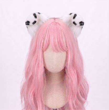 Large main product view of a pale mannequin head with long pastel pink hair wearing a discreet metal headband featuring large, fluffy white faux fur puppy ears with striking black dalmatian spots, perfect for submissive pet play and cosplay.