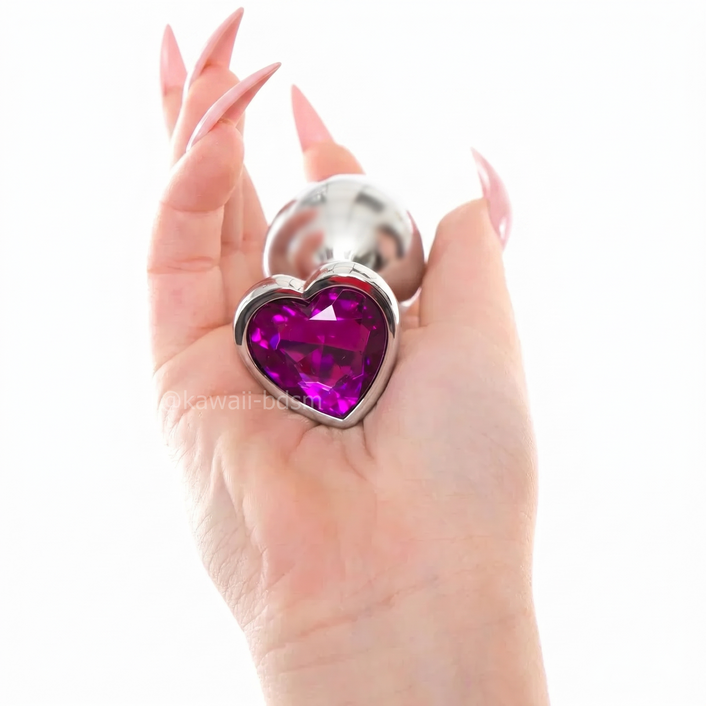 Close-up of a hand holding the large size purple crystal heart stainless steel plug, showing the beautiful faceted heart gem.
