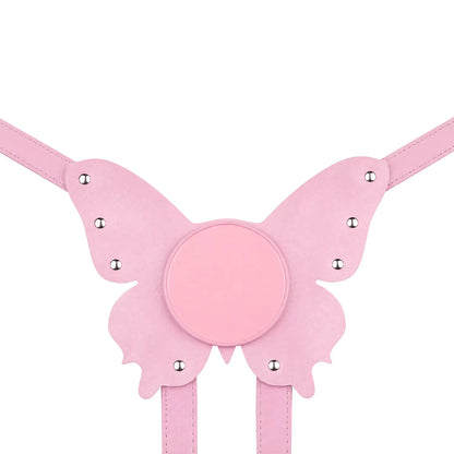 A flat lay of the pastel pink butterfly strap-on harness plate, perfectly displaying its unique structured shape, vegan leather texture, and smooth suction cup base.