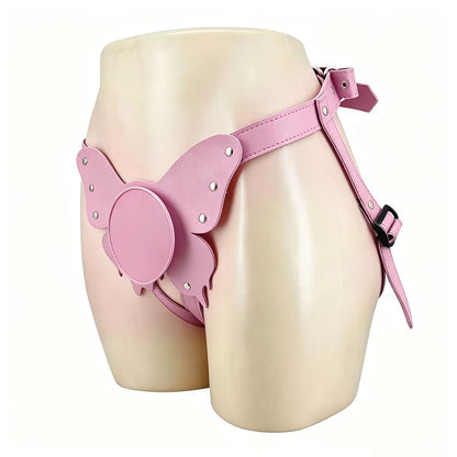 A side-angle view of the pastel pink butterfly suction cup harness worn on a solid mannequin torso. The image highlights the flat center base, silver studs, and the secure side buckle fastening.