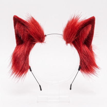 Bright red fluffy faux fur cosplay ears attached to a wire headband, isolated against a pristine white background.