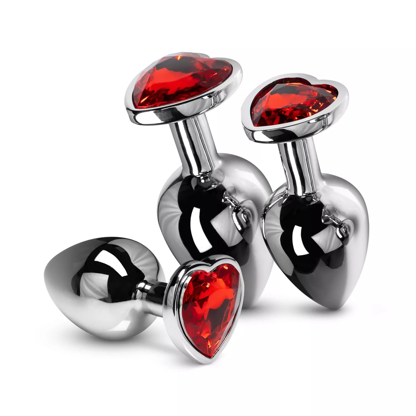 Three ruby red crystal heart stainless steel plugs standing upright, displaying the small, medium, and large progression.