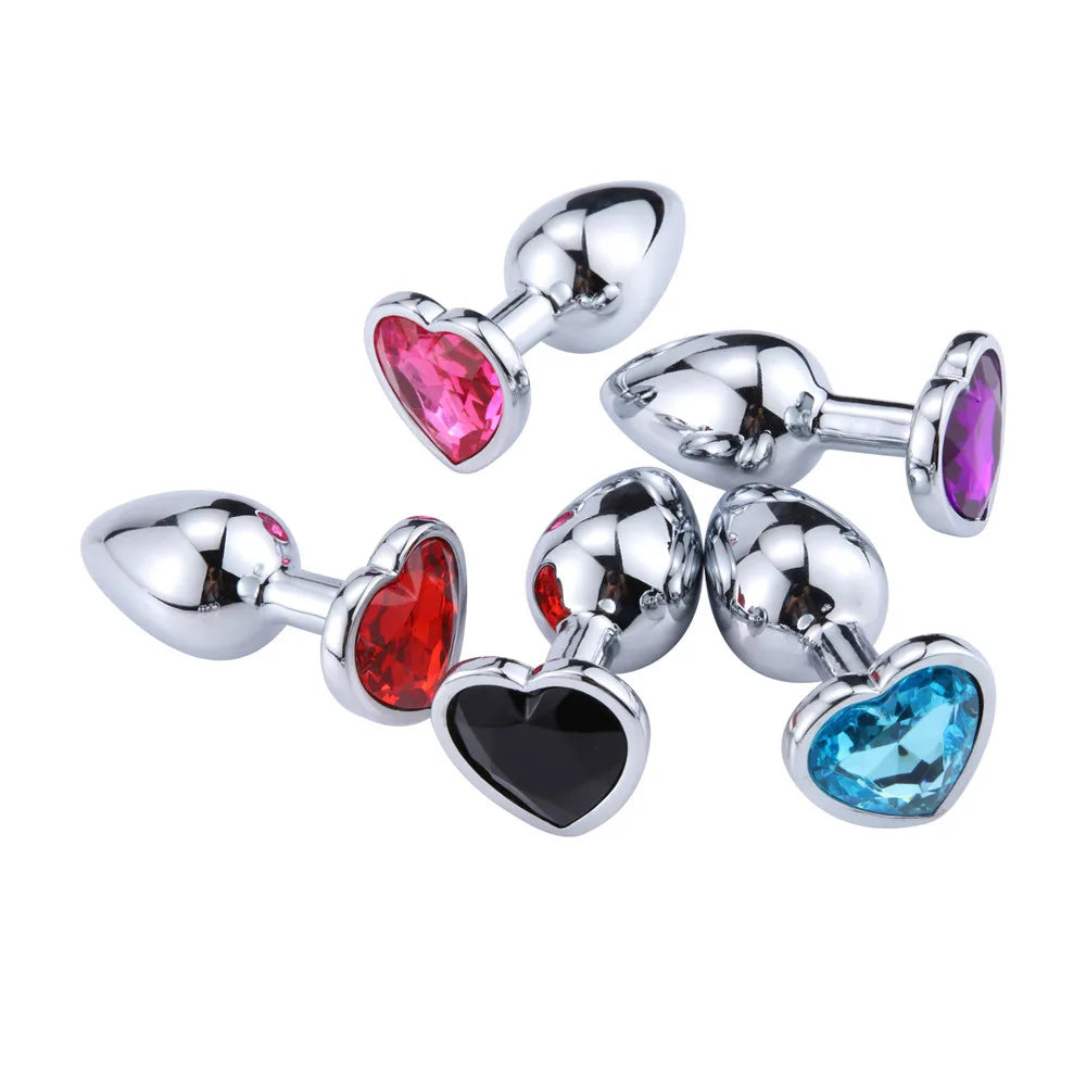 A scattered assortment of crystal heart stainless steel plugs showing vibrant colors like red, blue, black, and pink.