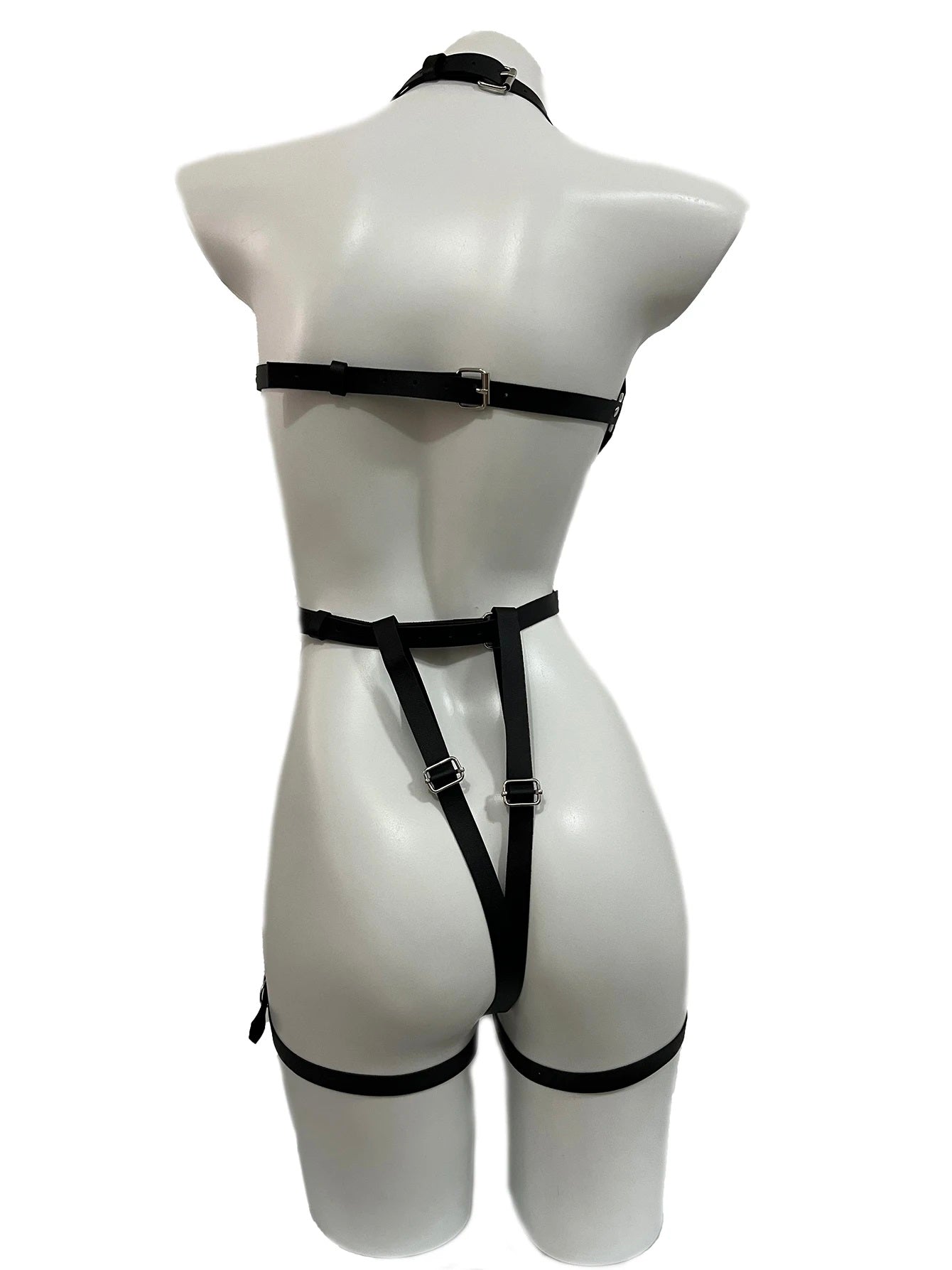 Back view of a black full-body faux leather harness on a mannequin, showcasing adjustable back straps, a thong-style bottom strap, and thigh garters. Edgy BDSM fashion