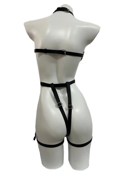 Back view of a black full-body faux leather harness on a mannequin, showcasing adjustable back straps, a thong-style bottom strap, and thigh garters. Edgy BDSM fashion