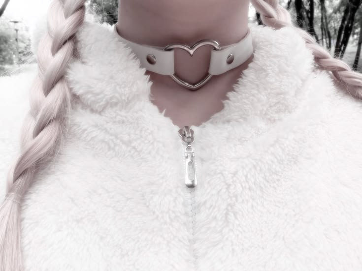 A cozy lifestyle shot of a model wearing a white heart choker paired with a fluffy white jacket.