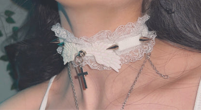 Close-up shot of the white lace ruffled choker being worn, showcasing the contrasting silver spikes, central angel wings, and hanging cross.