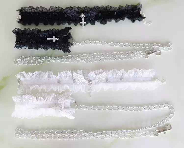 photograph of both the black and white ruffled lace chokers, arranged side-by-side on a clean, soft background. A full product view showcasing all details: central angel wings, silver spikes, and cross pendants.