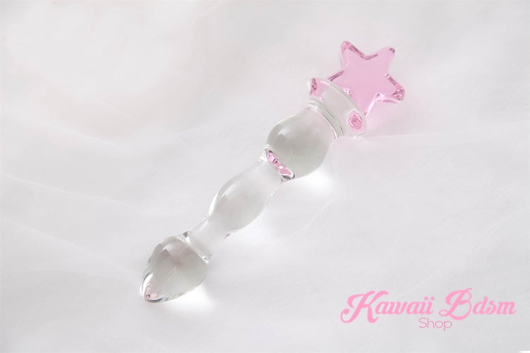 Clear glass celestial wand with a cute pink star handle resting elegantly on soft white silk fabric.