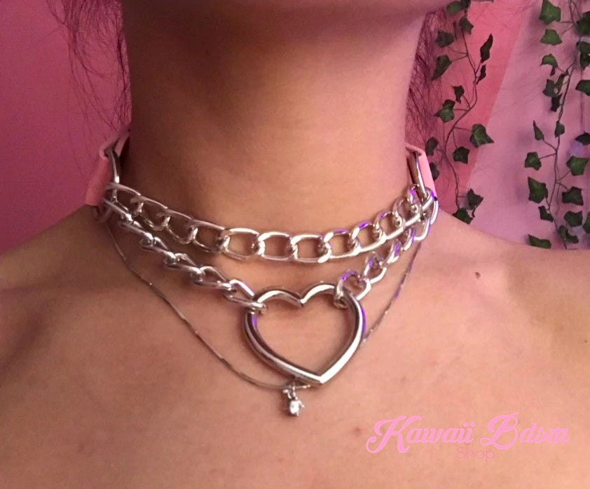 Detailed lifestyle close-up shot of a model's neck wearing the silver double chain heart choker against a pink background.