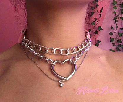 Detailed lifestyle close-up shot of a model's neck wearing the silver double chain heart choker against a pink background.