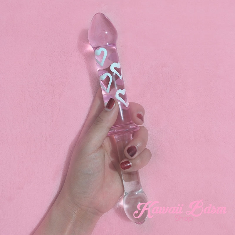 Hand holding the double ended pink and clear glass dildo against a solid bright pink background.