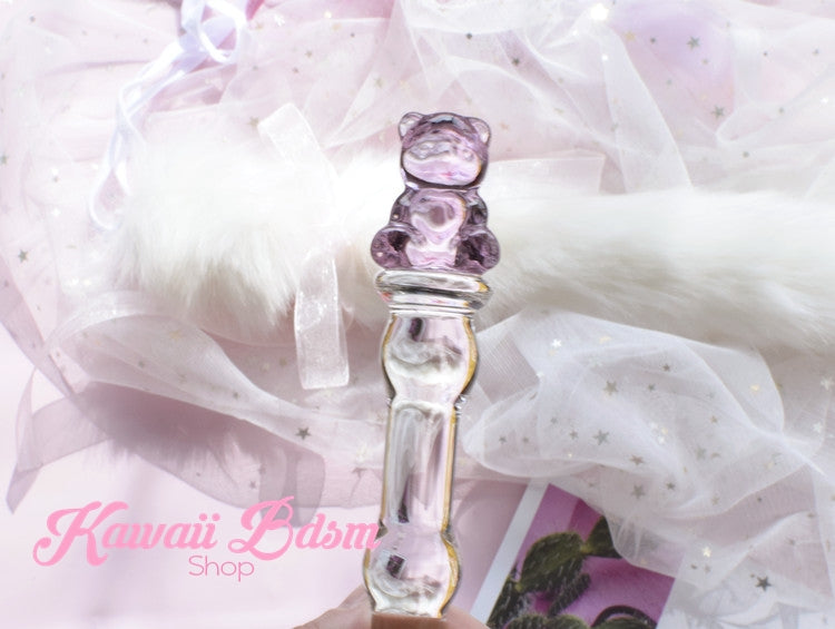 Hand holding the slim pink teddy bear glass wand against a soft white tulle fabric background.