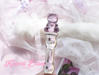 Hand holding the slim pink teddy bear glass wand against a soft white tulle fabric background.