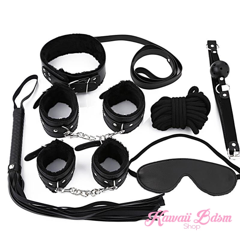 Complete midnight black 7-piece starter bondage set with vegan leather cuffs, collar, whip, and blindfold on a white background.