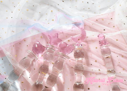 A collection of multiple petite glass pleasure wands resting on soft white silk and pastel pink ribbons.