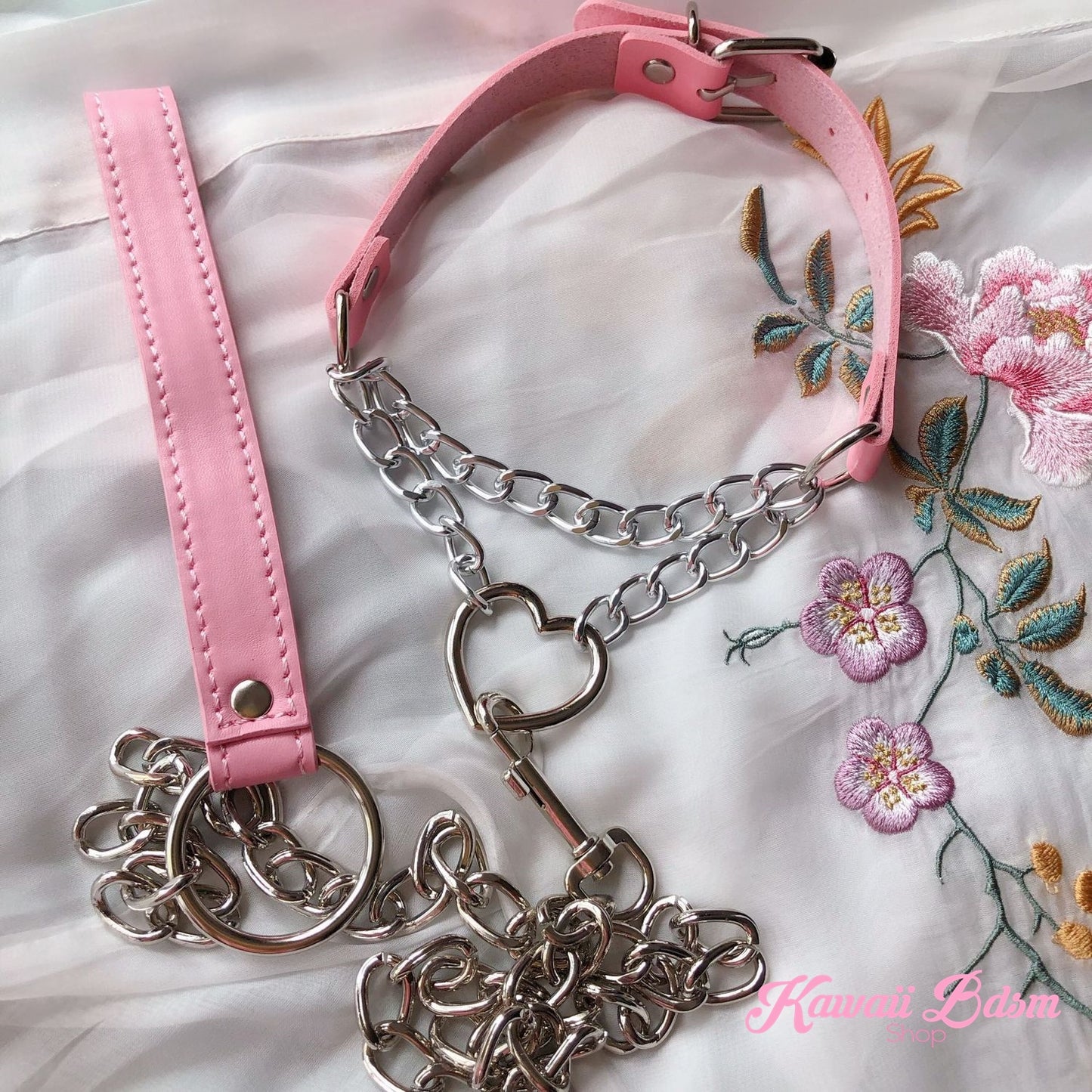 Flatlay display of the pastel pink leather choker and matching pink leather leash set, featuring silver hardware and decorative floral props.