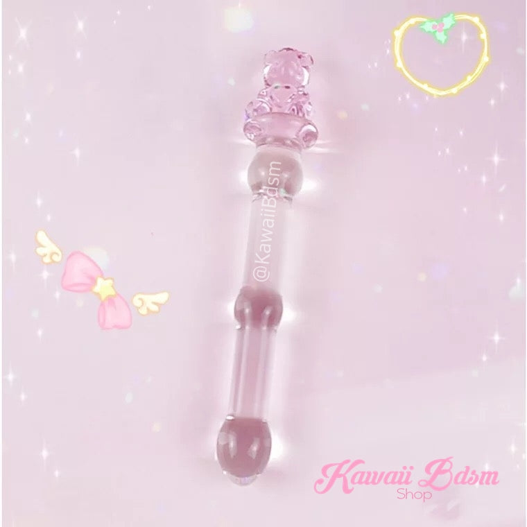 The delicate pink teddy bear glass pleasure wand resting diagonally on a pastel pink background with a small drawn yellow heart.