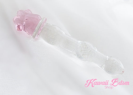 Kawaii glass paw wand resting on white fabric, highlighting the smooth ribbed texture and adorable pink paw base.