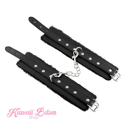 A pair of black fluffy restraint cuffs laid flat and unbuckled, displaying the durable vegan leather exterior and strong metal chain.