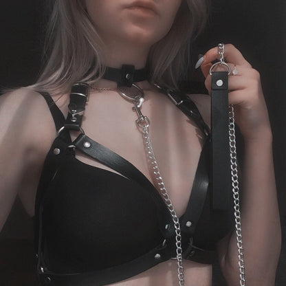 Model wearing the black Baby Dom harness attached to a metal chain leash for kinky roleplay and pet play.